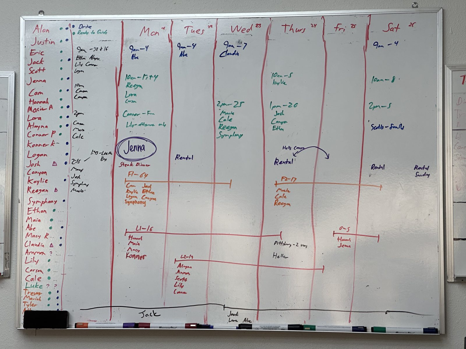 A large whiteboard covered in hand-written names, dates, and colored lines: the operations schedule for a multi-base rafting company before it was replaced by software.